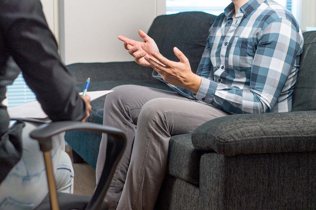 A man sitting on a sofa sharing his values in addiction recovery that guide his recovery journey.