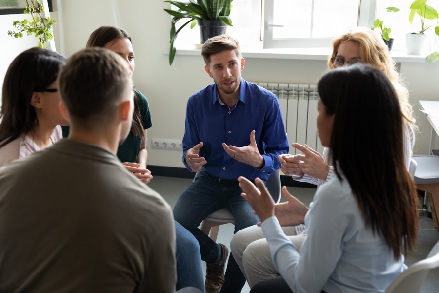 a group of people sitting in a circle talking during addiction therapy