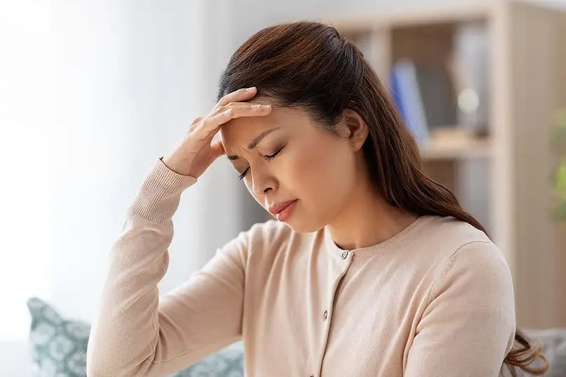 a woman with headache holding her head due to xanax side effects