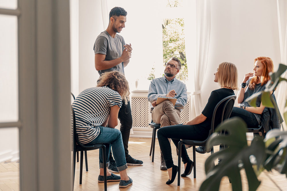 Group of individuals engaging in a peer support session for recovery