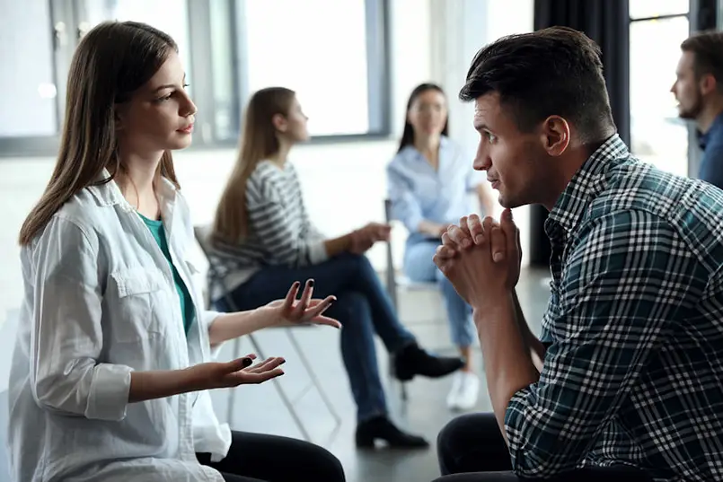 a man and woman sitting in a circle discussing boundaries in recovery