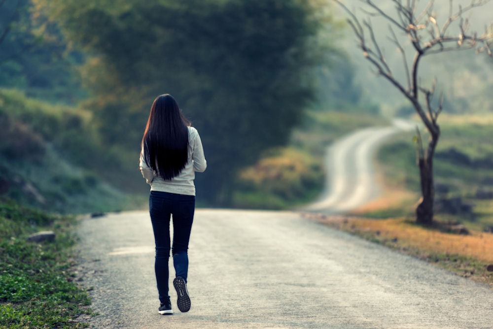 Woman walking on a road as a guide to the 12 Promises of AA