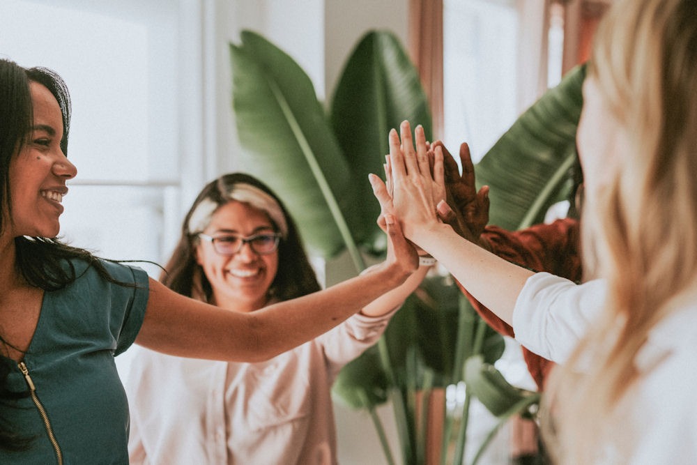 Group of women giving high-fives during a Dialectical Behavior Therapy (DBT) session.