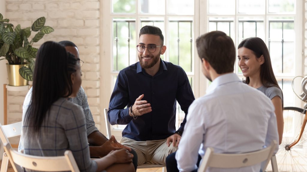 a man in a blue sweater addressing a small therapy group about OxyContin
