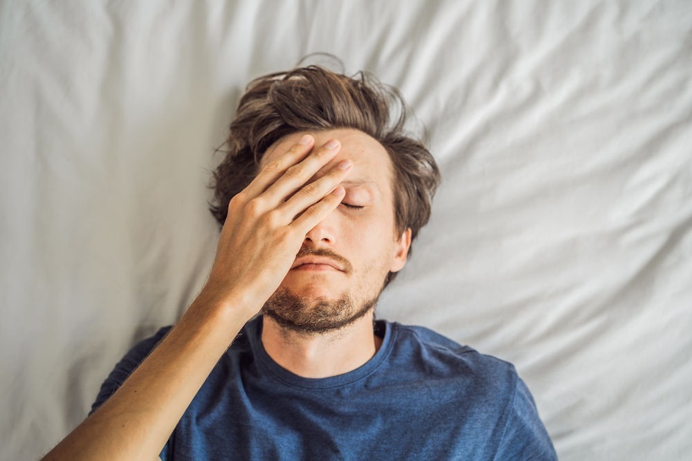 Man lying on bed, thinking about how drinking alcohol can thin his blood