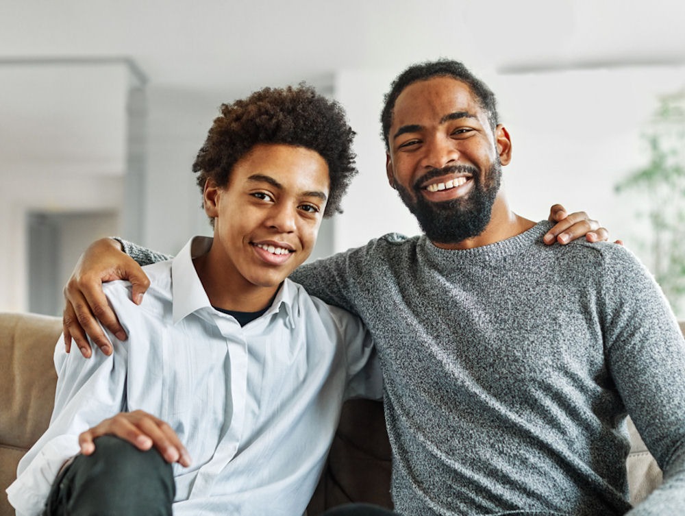 A father and son sitting together and smiling as accountability partners in recovery