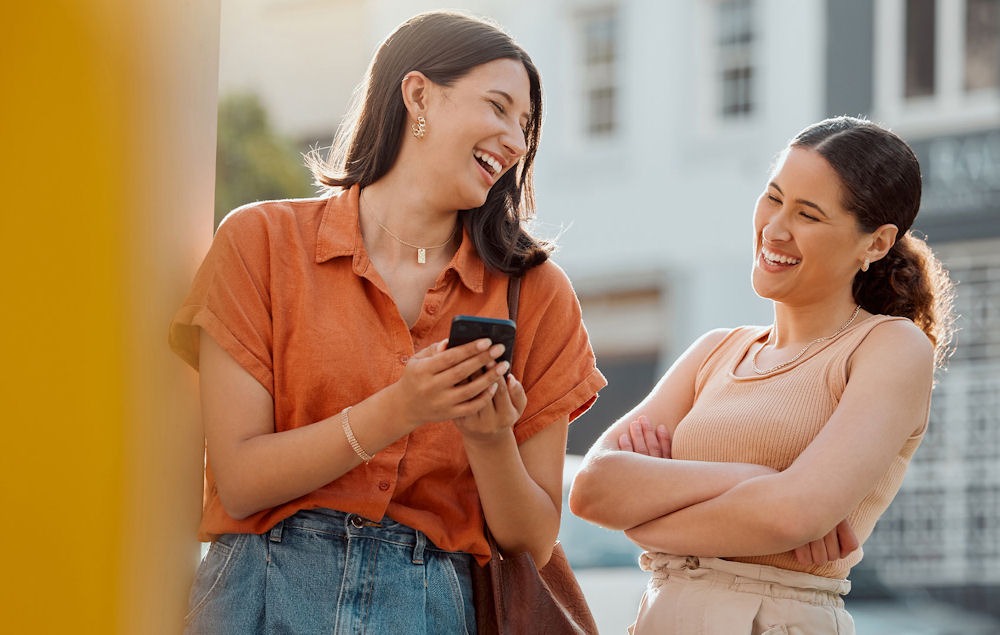 Two women outside laughing, serving as accountability partners in recovery.