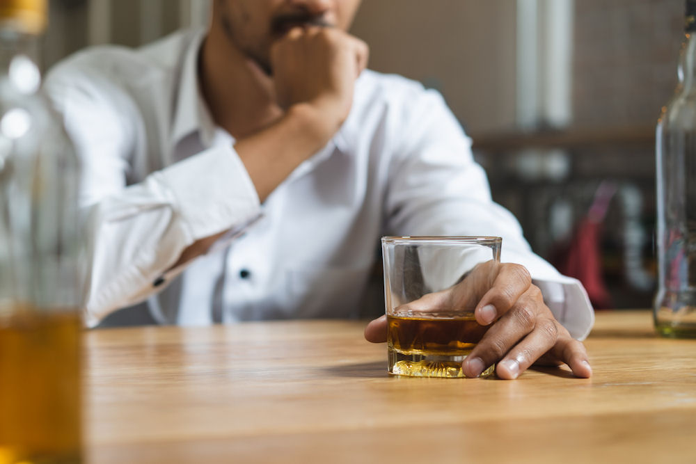 man staring at highball glass wonders is alcohol addictive?