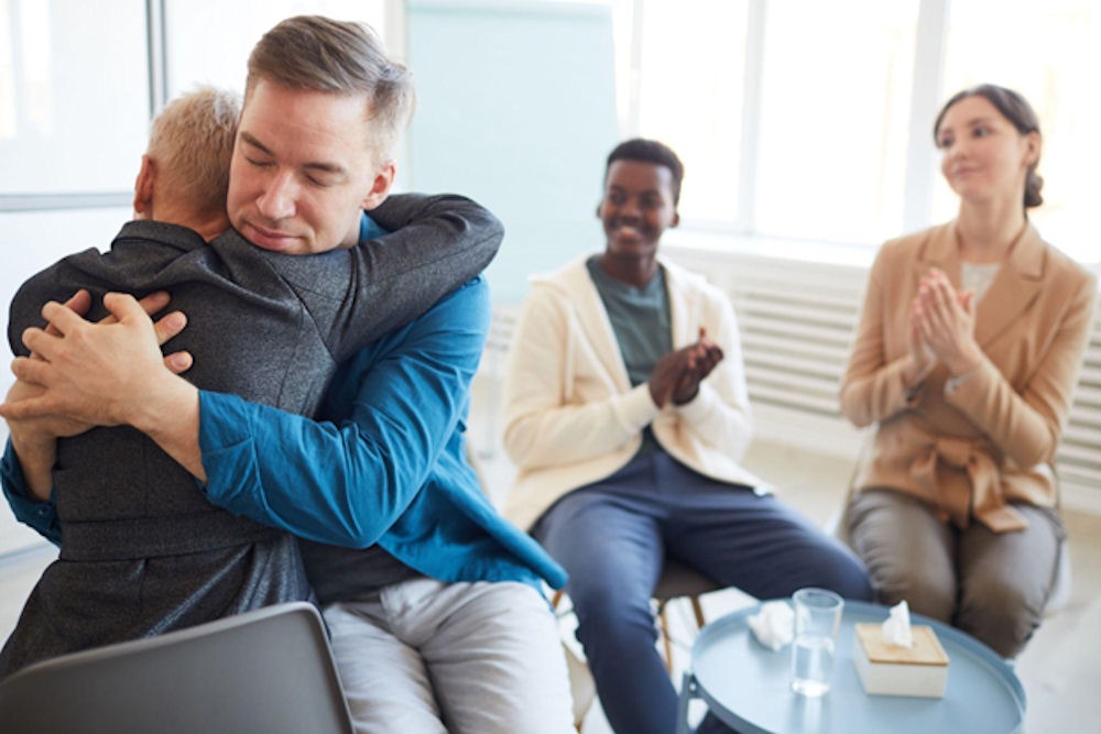 Two people hugging during a group therapy session for a gender-specific rehab program