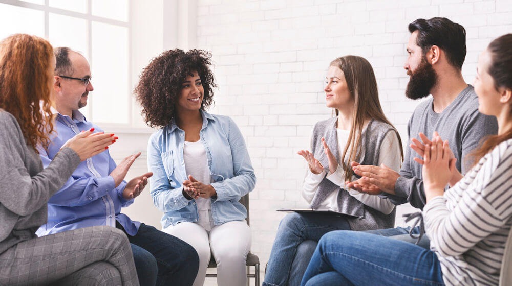 Group of individuals clapping in therapy session at an evidence‑based treatment center