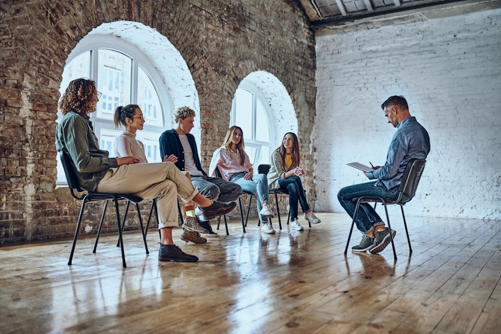 Individuals in group therapy discussing the role of community support in mental health recovery