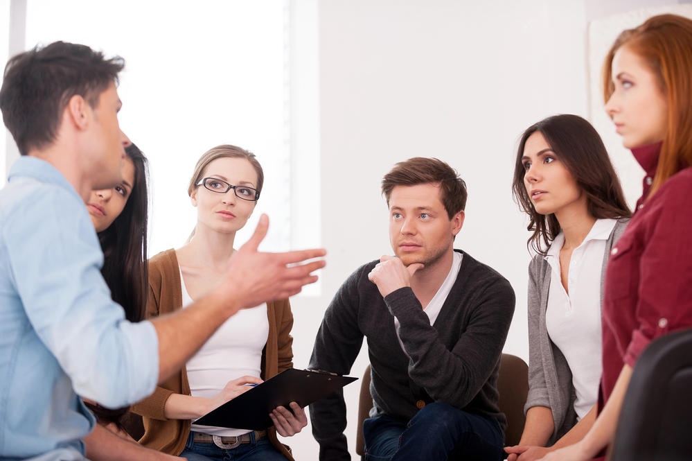 a man in a group explaining the pros and cons of Magellan insurance