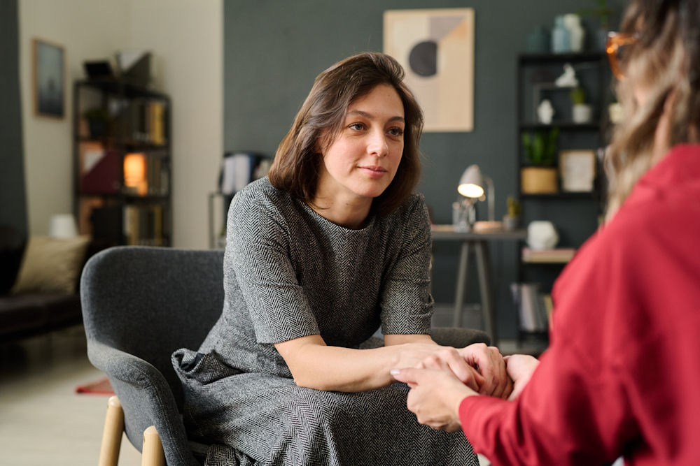 therapist holding patient’s hands during session on childhood trauma in adults