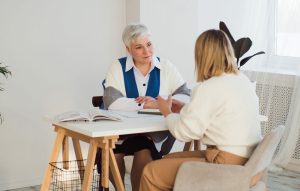 Mental health therapist providing supportive counseling to a woman addressing depression and menopause during a one-on-one therapy session.
