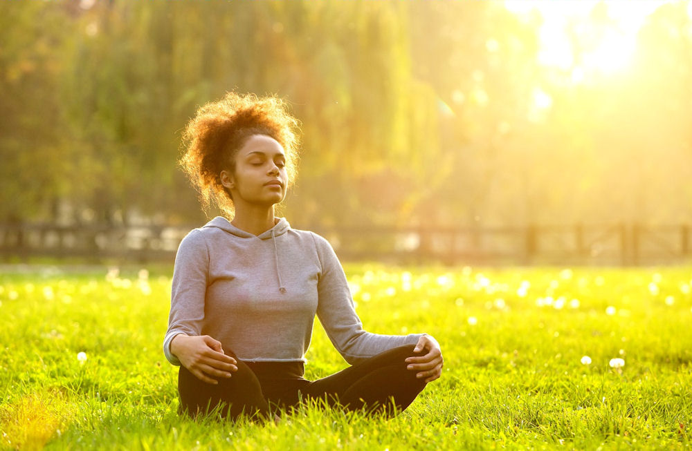 a woman meditating in the grass