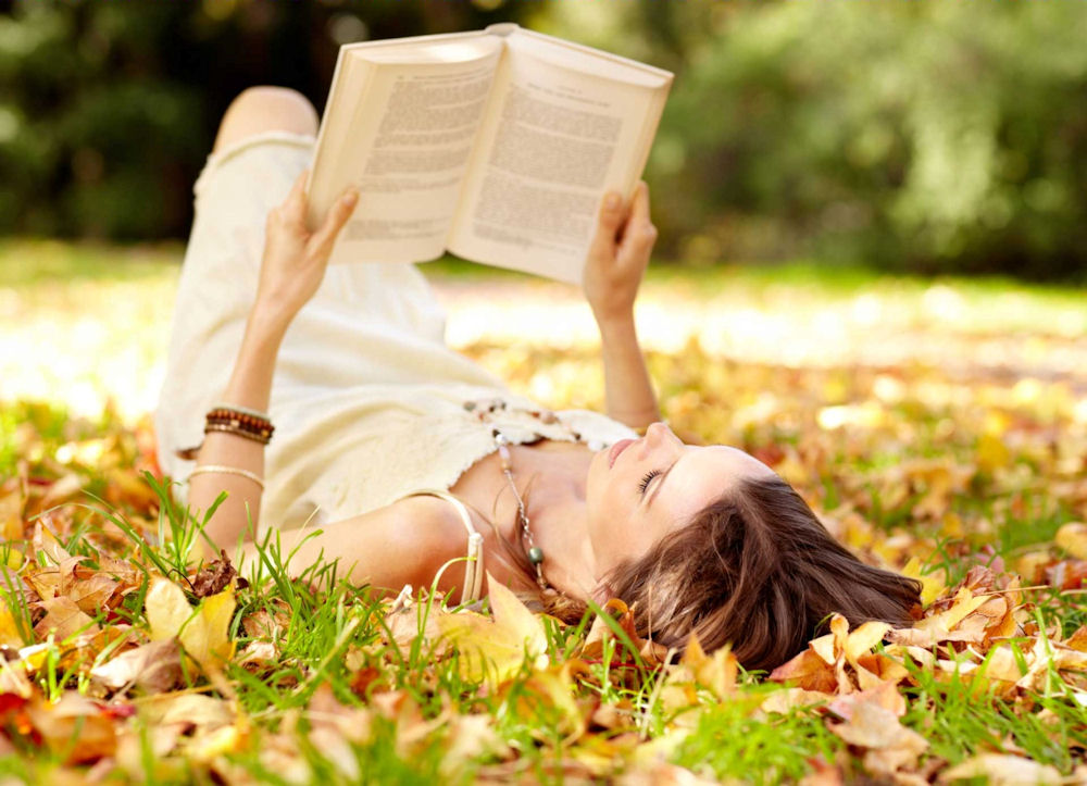 a woman reading laying in the grass
