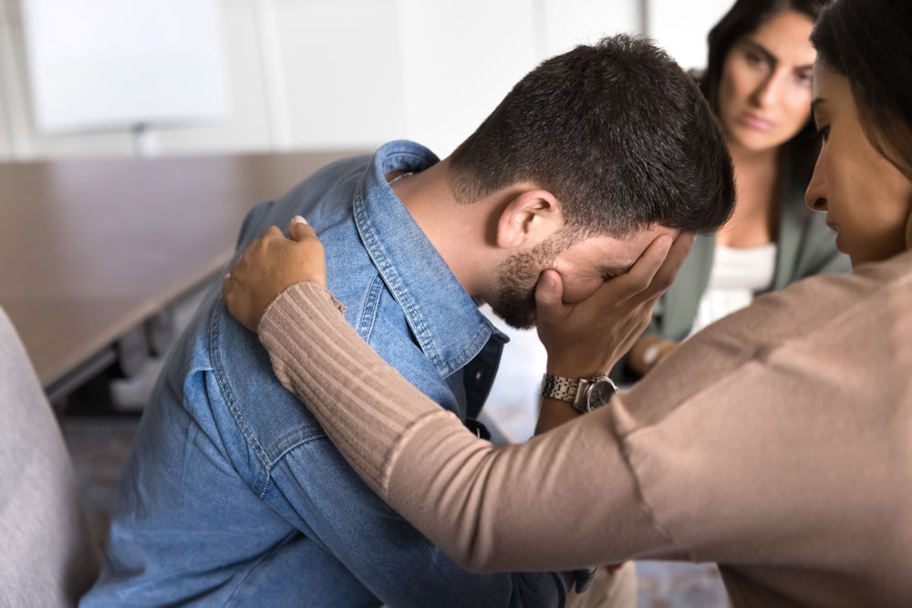 Loved ones comforting a man during a difficult moment, representing family support in residential treatment.