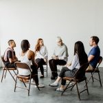 Group of people seated in a therapy circle participating in a discussion, depicting a group session in inpatient rehabilitation.